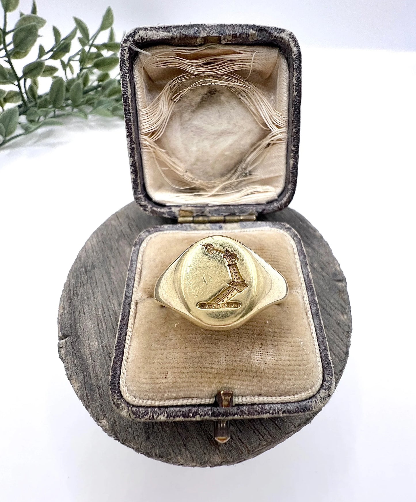 A yellow gold oval signet ring with a seal engraved heraldic crest in an antique ring box