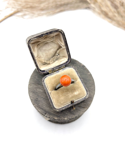 A round orange coral and diamond dress ring in platinum, in an antique ring box