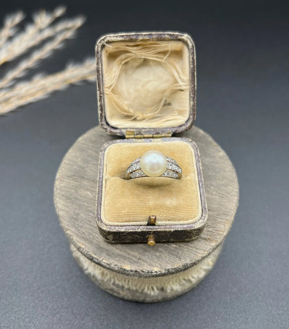 A pearl and diamond ring in platinum, in an antique ring box