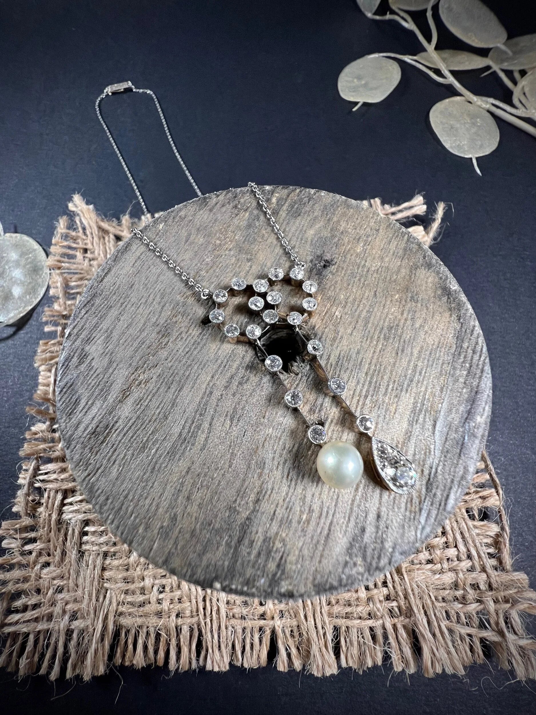 An antique diamond and pearl double drop pendant necklace, on a wooden spool