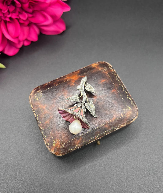 A pink enamel, diamond and pearl flower pendant in gold and silver, on an antique box