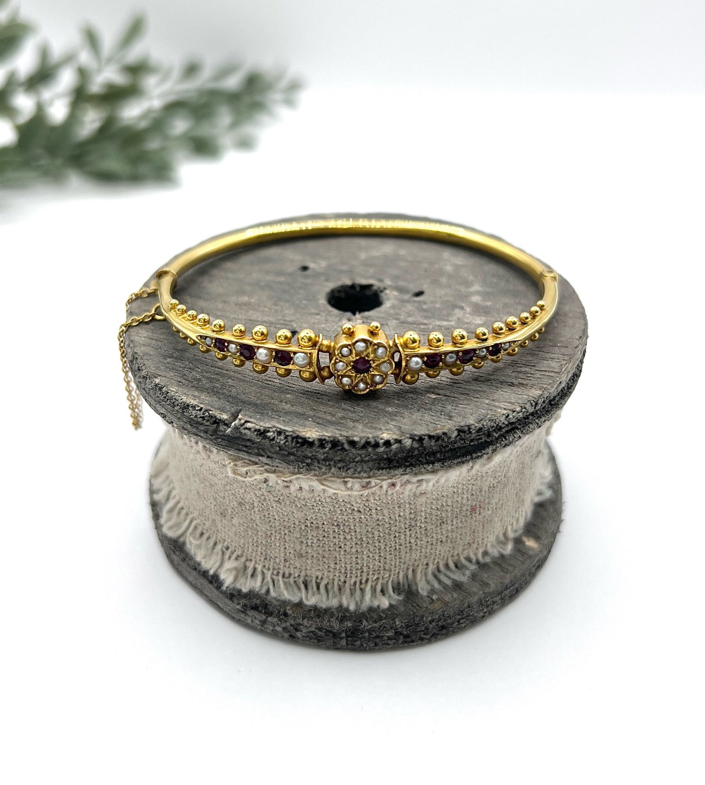 A yellow gold bangle bracelet set with rubies and seed pearls