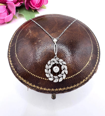 A platinum floral wreath pendant with diamonds on a platinum chain