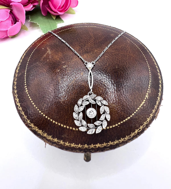 A platinum floral wreath pendant with diamonds on a platinum chain
