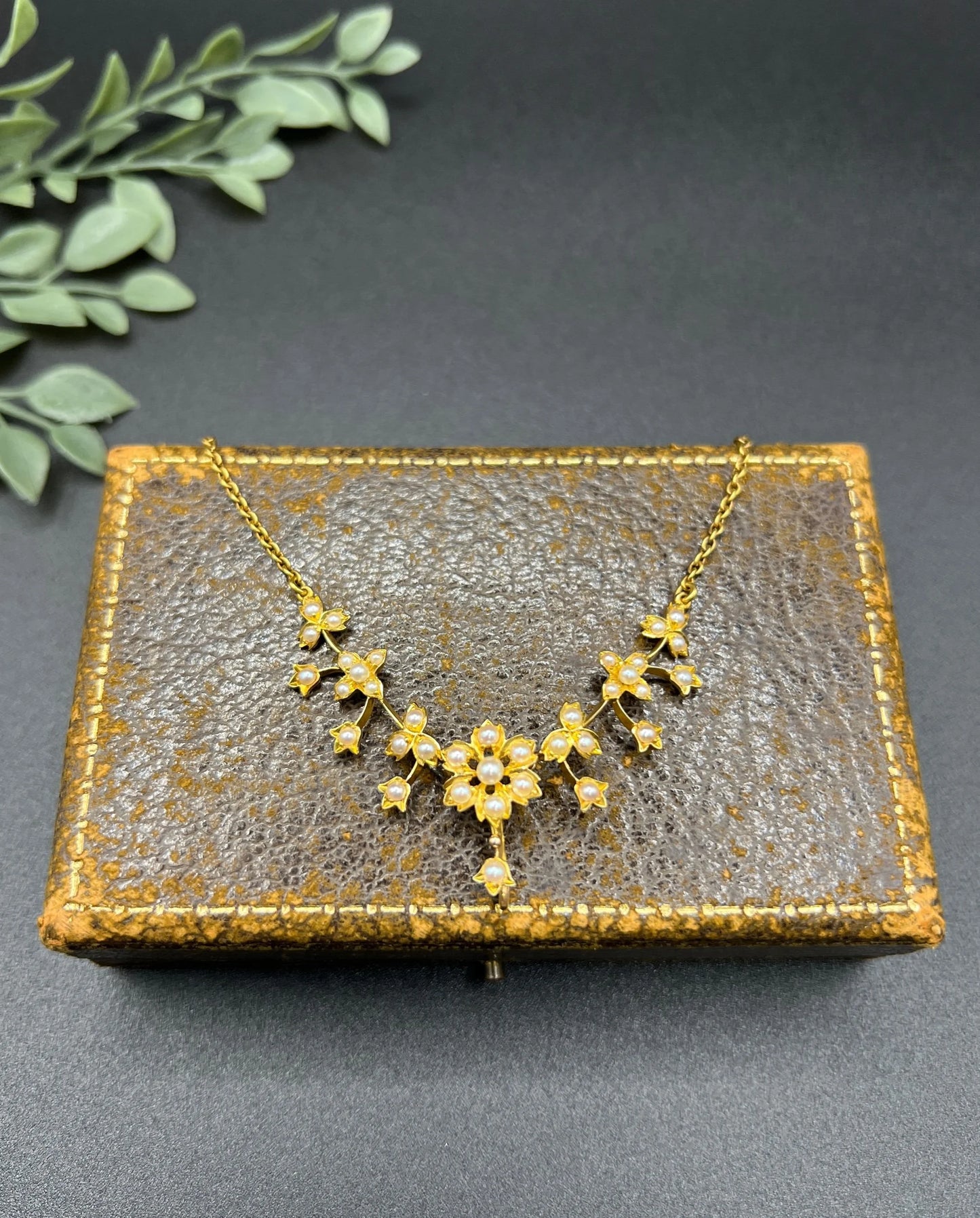 A yellow gold floral pendant necklace with seed pearls