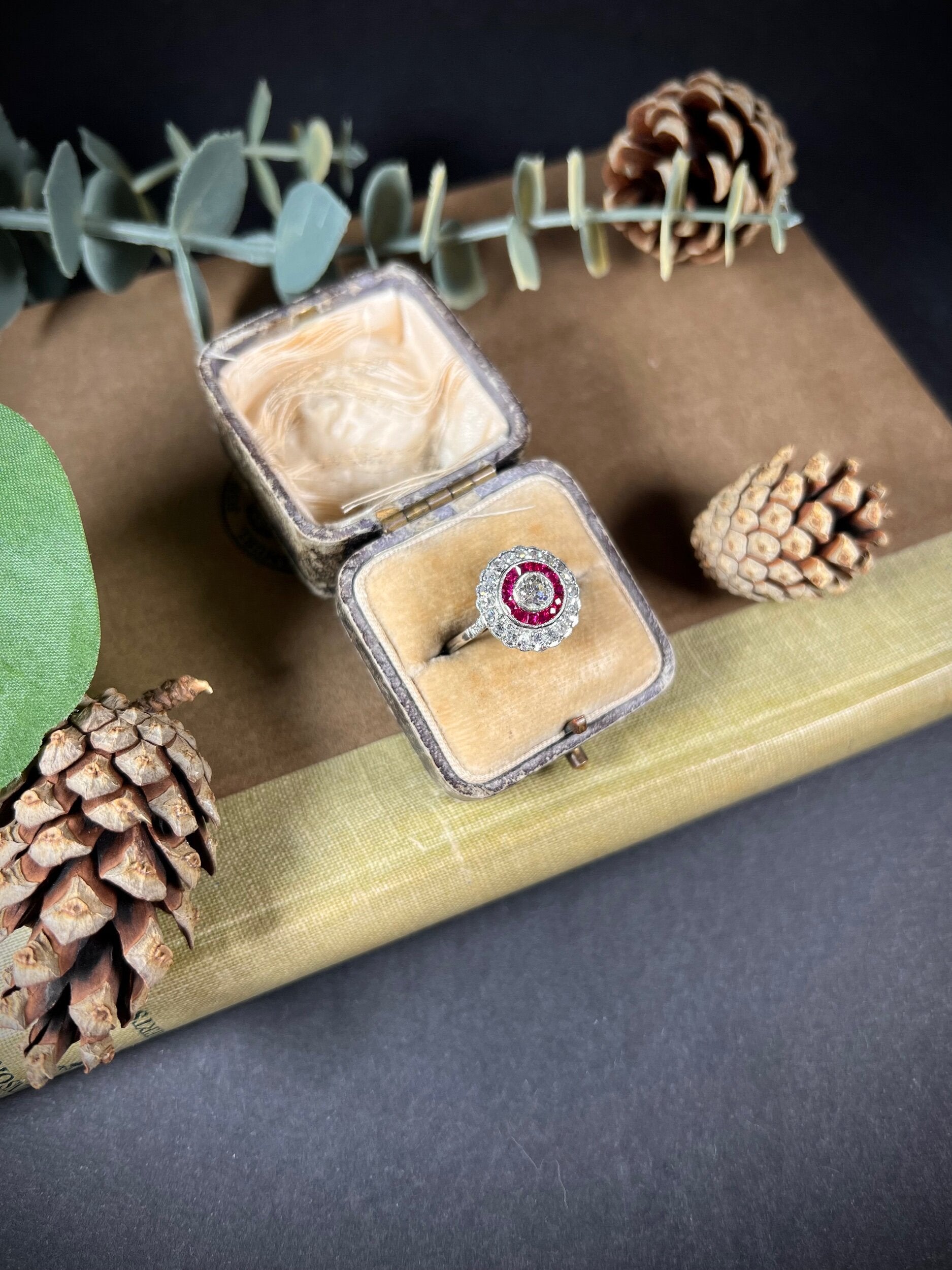 A round cluster ring with rubies and diamonds in white gold, in an antique ring box