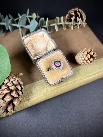 A round cluster ring with rubies and diamonds in white gold, in an antique ring box