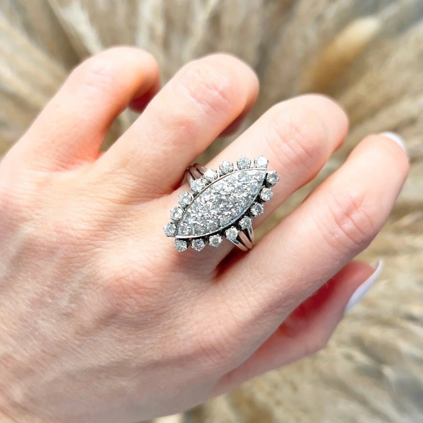 A navette shaped diamond cluster ring in white metal, modelled on a hand