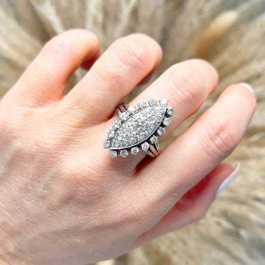 A navette shaped diamond cluster ring in white metal, modelled on a hand