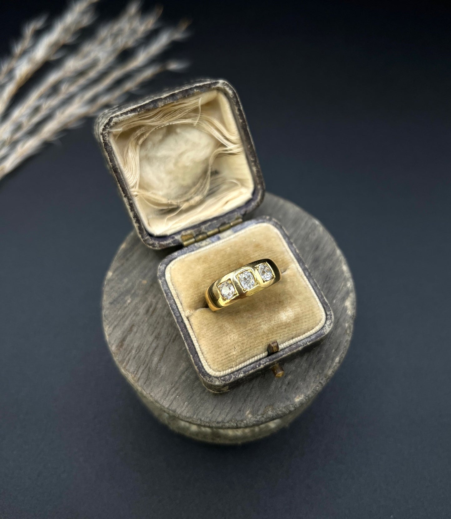 A three stone old cut diamond ring in yellow gold, in an antique ring box