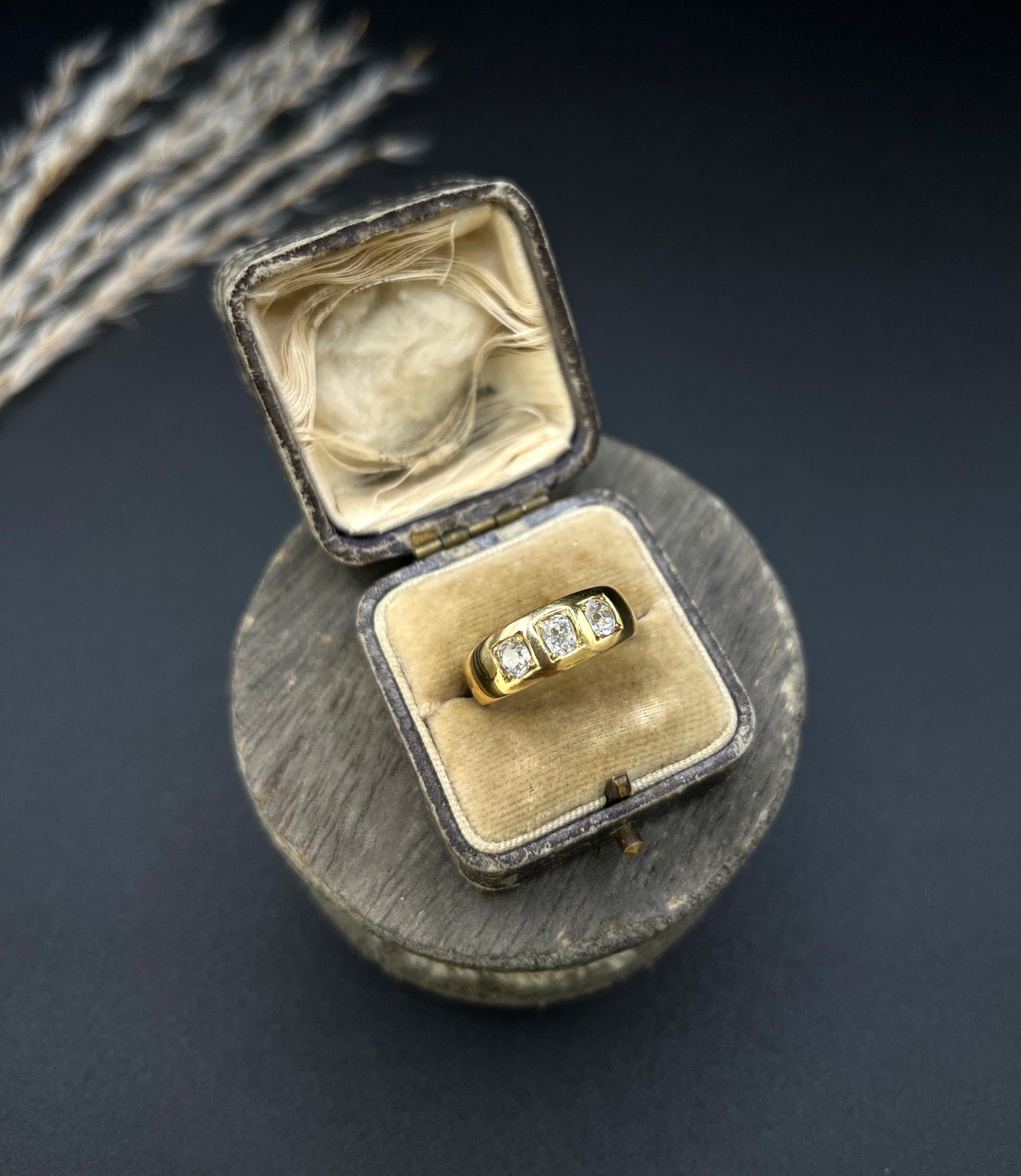 A three stone old cut diamond ring in yellow gold, in an antique ring box