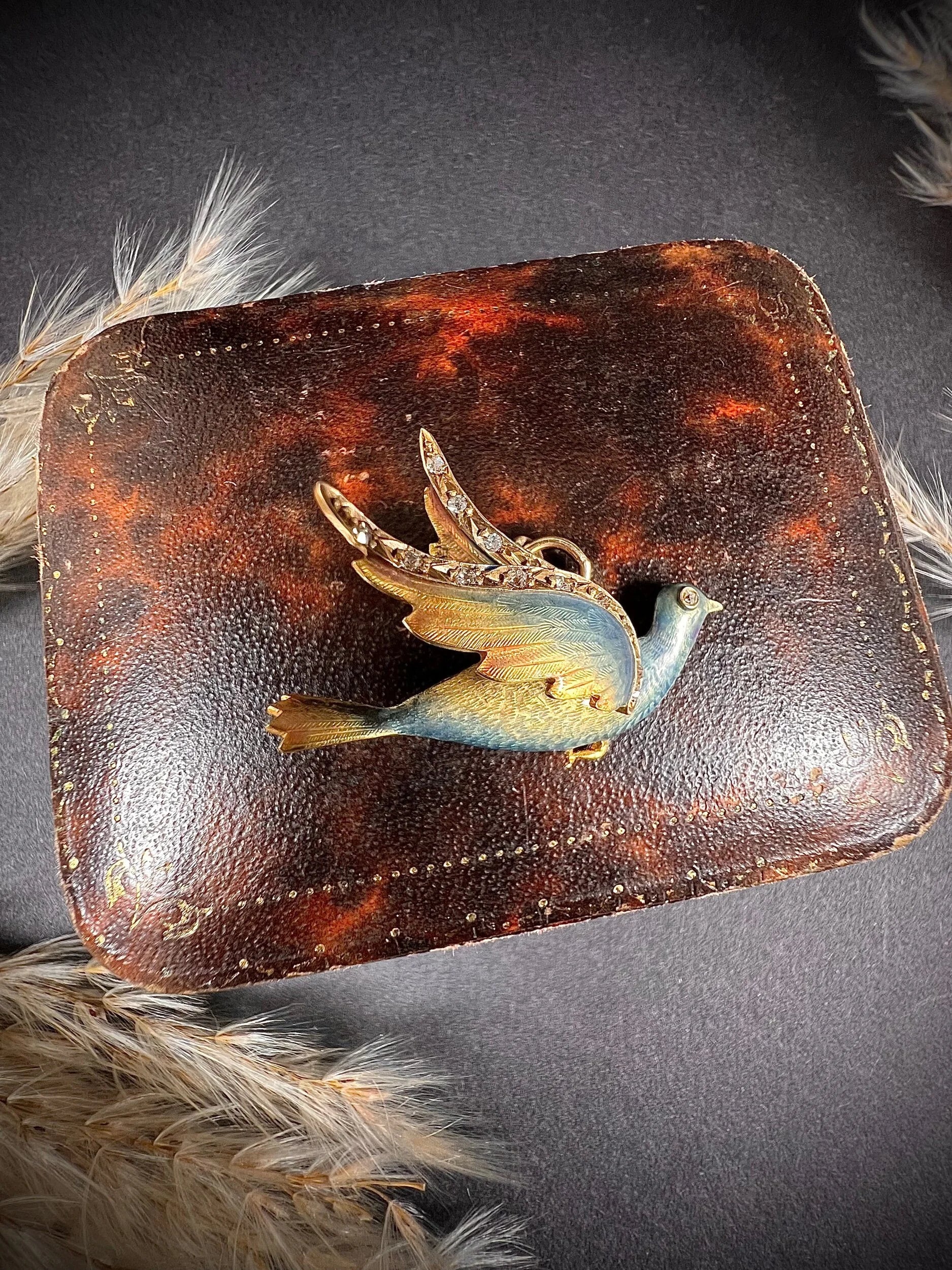 An enamel and diamond dove bird pendant, on an antique box