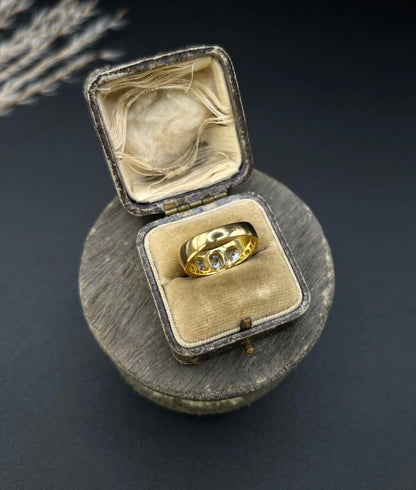 A three stone old cut diamond ring in yellow gold, in an antique ring box