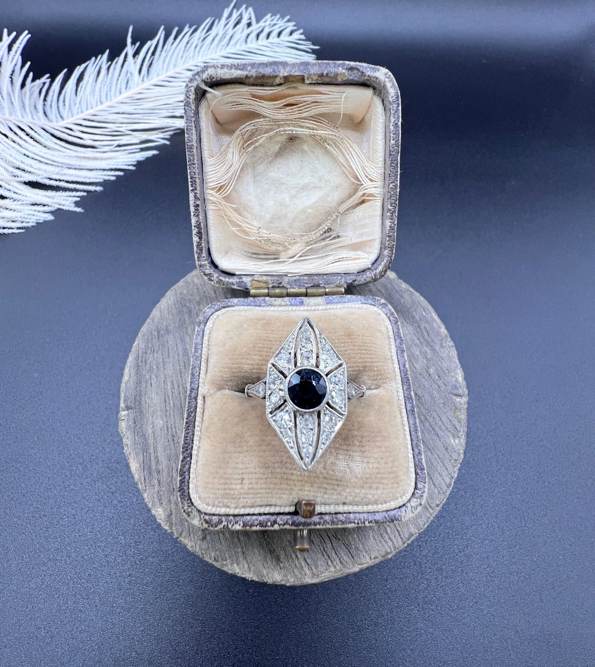 A navette shaped cluster cocktail ring with a sapphire centre surrounded by diamonds, in platinum, in an antique ring box
