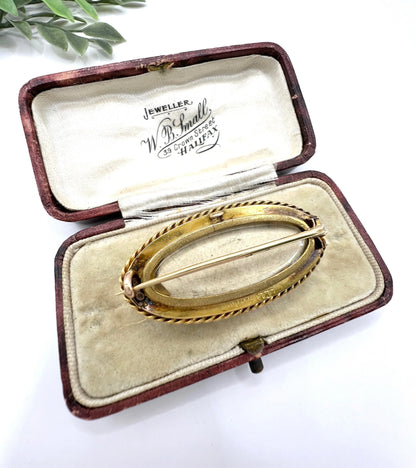 An oval yellow gold brooch with a locket compartment, in an antique box