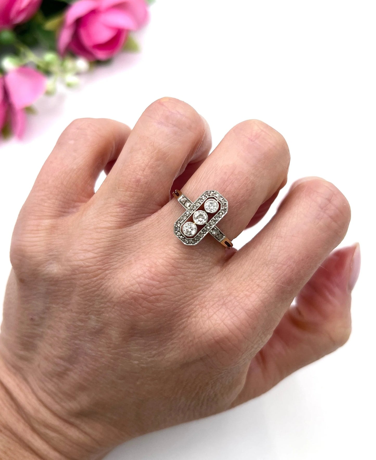 A diamond open cluster ring with three principal diamonds, in yellow and white gold, modelled on a hand