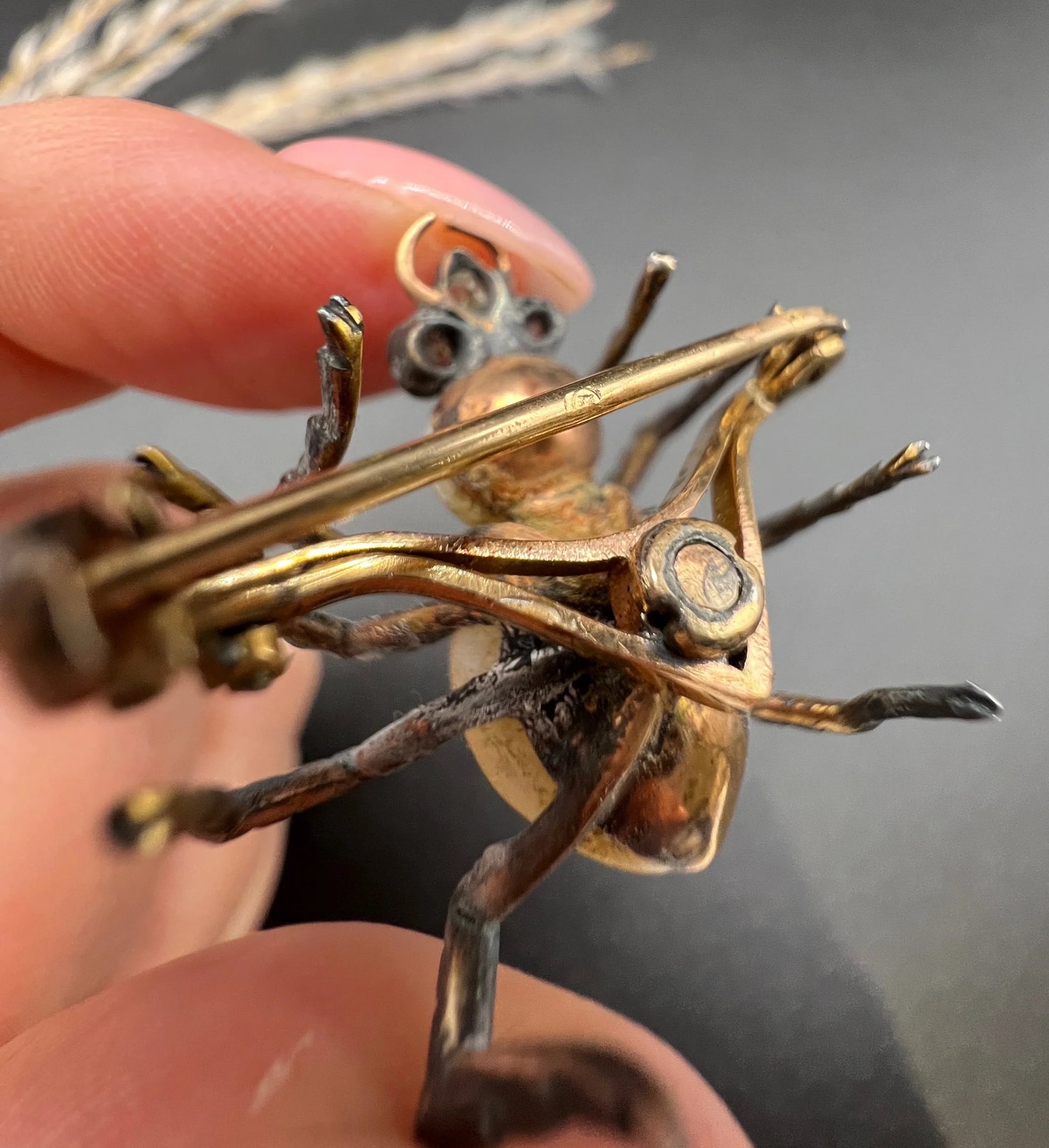 A pearl and diamond spider brooch in gold and silver, held in a hand