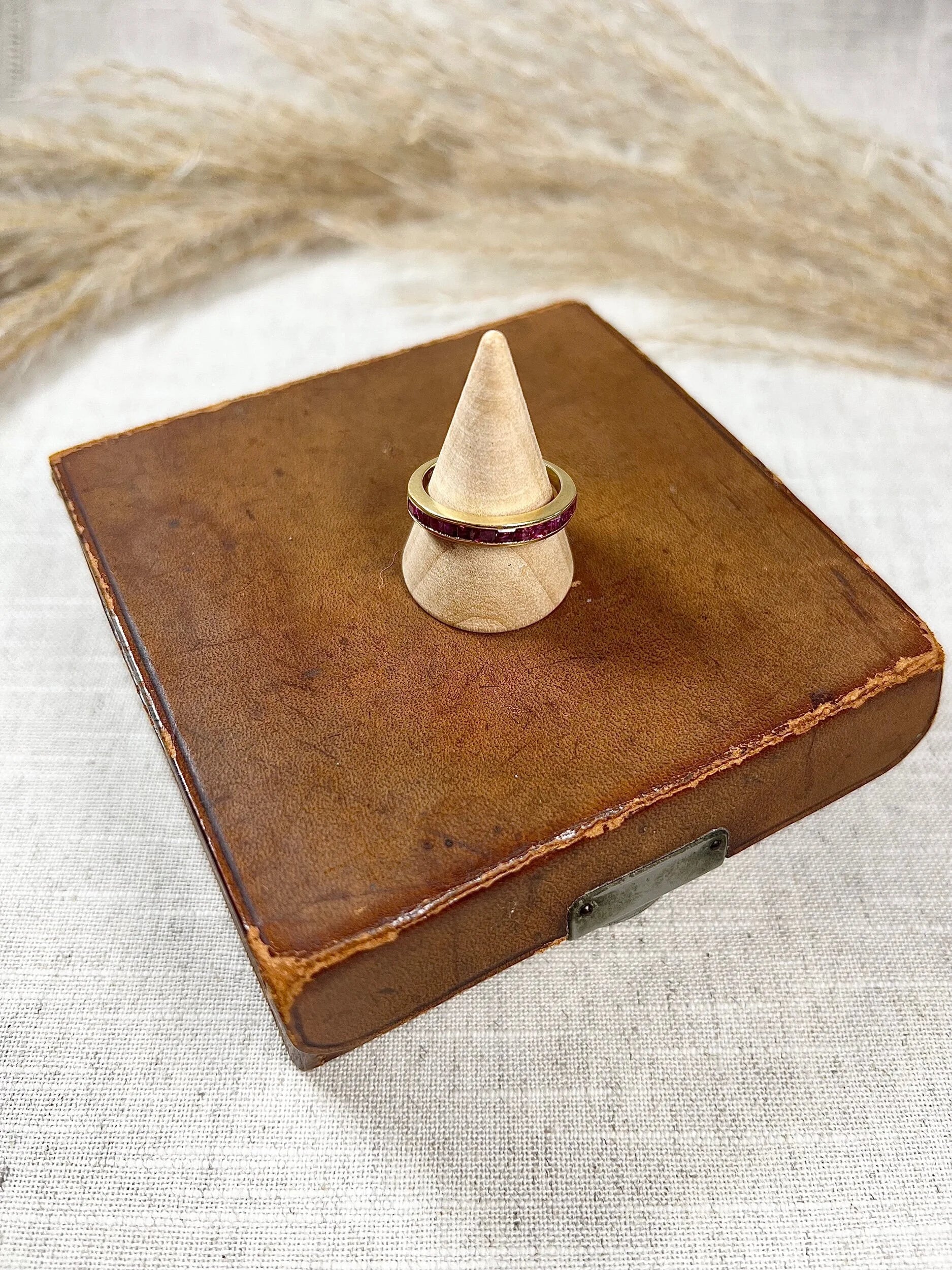 A yellow gold ruby channel set eternity band, on a wooden ring cone