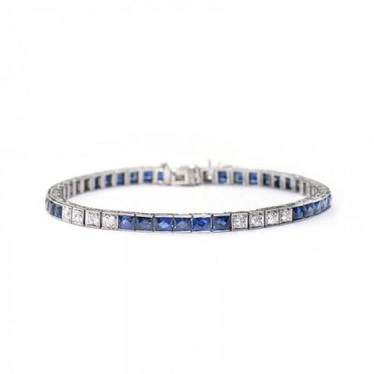 Antique Art Deco Sapphire and Diamond Line Bracelet; alternating pattern of six French-cut sapphires in channel settings and four round brilliant-cut diamonds in box settings. Crafted from platinum, all settings are individually hinged with millegrain edges. The sides are engraved with a millegrain and foliate design. Circa 1935