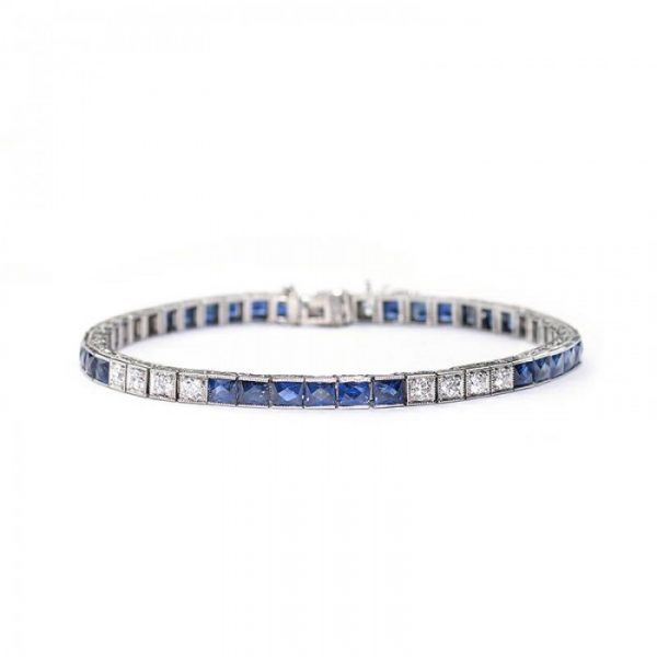 Antique Art Deco Sapphire and Diamond Line Bracelet; alternating pattern of six French-cut sapphires in channel settings and four round brilliant-cut diamonds in box settings. Crafted from platinum, all settings are individually hinged with millegrain edges. The sides are engraved with a millegrain and foliate design. Circa 1935