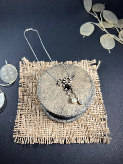 An antique diamond and pearl double drop pendant necklace, on a wooden spool