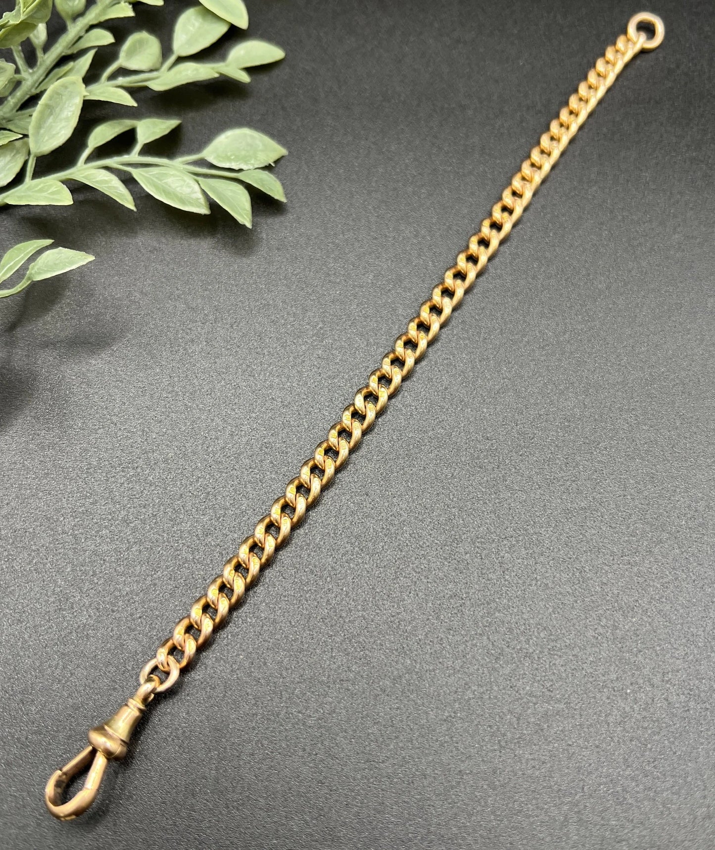 A gold curb link bracelet with a lobster claw clasp