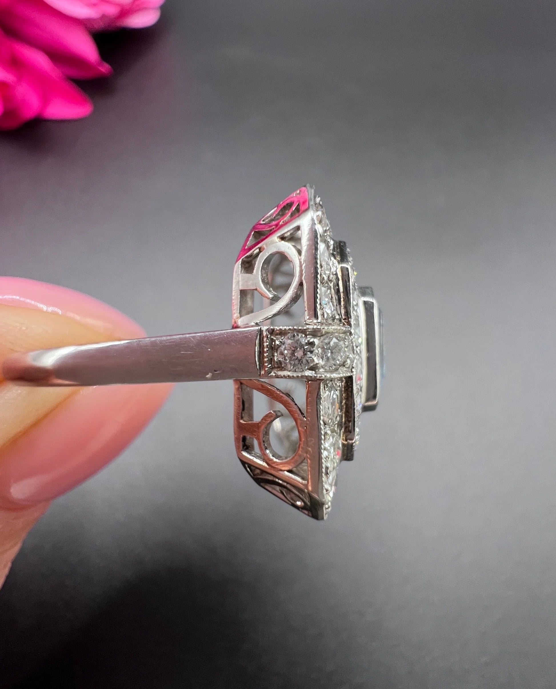 An octagonal shaped cluster ring with an aquamarine centre surrounded by two rows of diamonds, in platinum, held in a hand