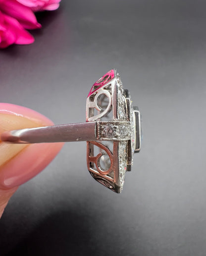 An octagonal shaped cluster ring with an aquamarine centre surrounded by two rows of diamonds, in platinum, held in a hand