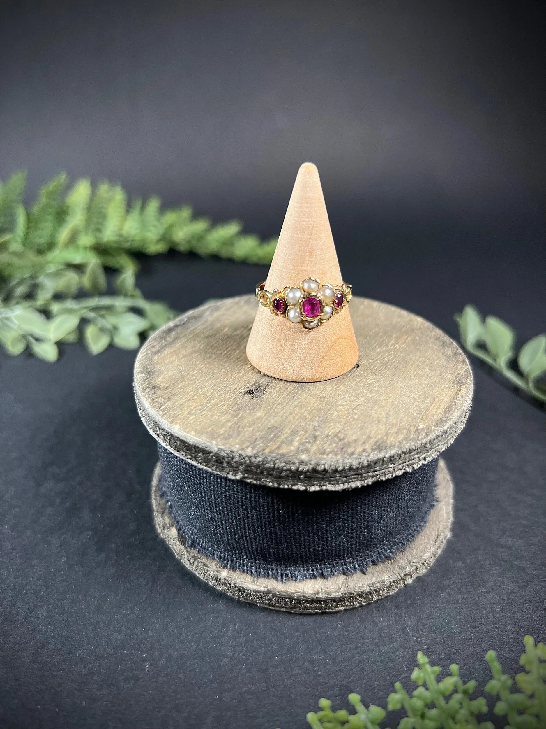 A yellow gold ruby and pearl floral cluster ring, on a ring cone