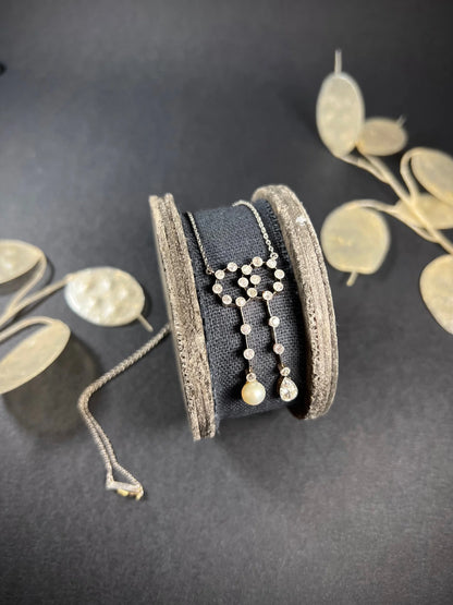 An antique diamond and pearl double drop pendant necklace, on a wooden spool