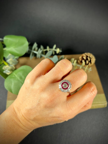 A round cluster ring with rubies and diamonds in white gold, modelled on a hand