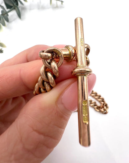 Close-up of a rose gold T-bar and curb links held in a hand