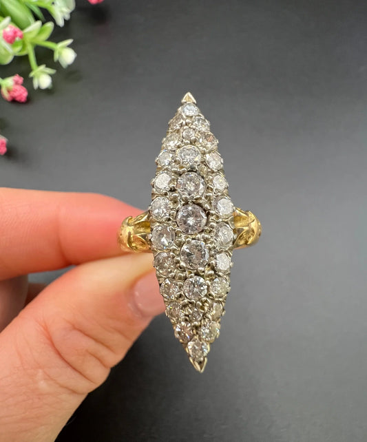 A navette shaped diamond cluster ring in yellow gold and silver, held in a hand