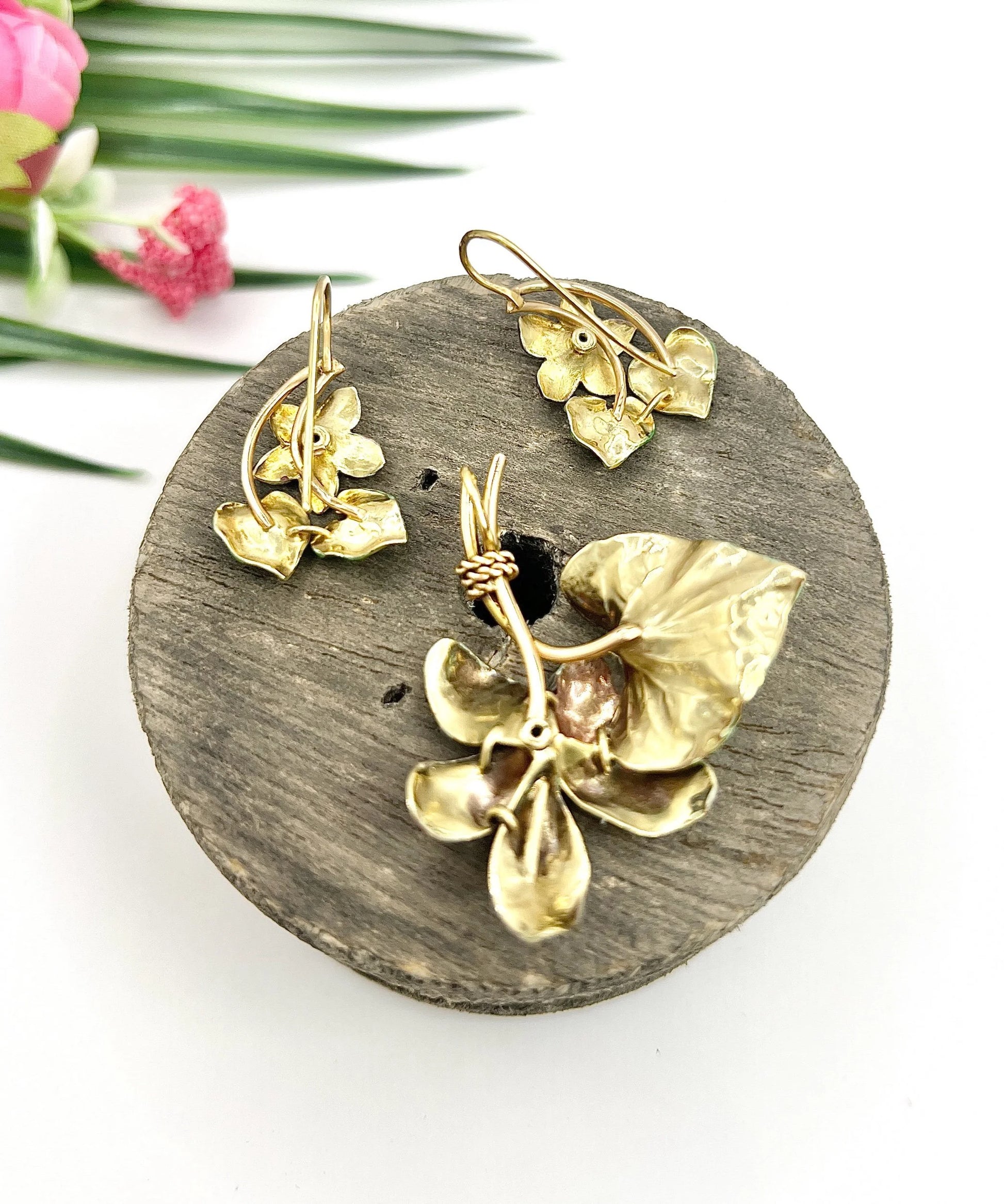 An enamelled flower suite comprising pendant and earrings, sitting on top of a wooden object