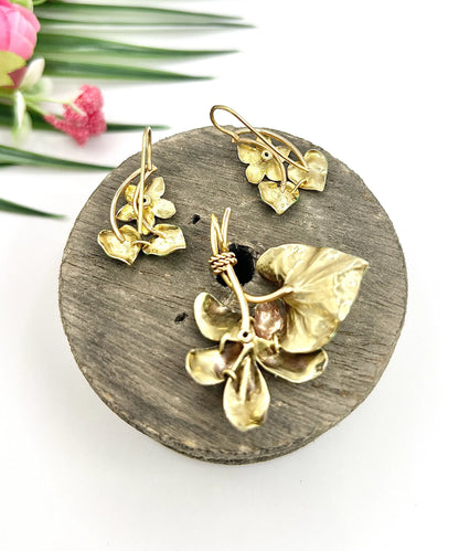 An enamelled flower suite comprising pendant and earrings, sitting on top of a wooden object