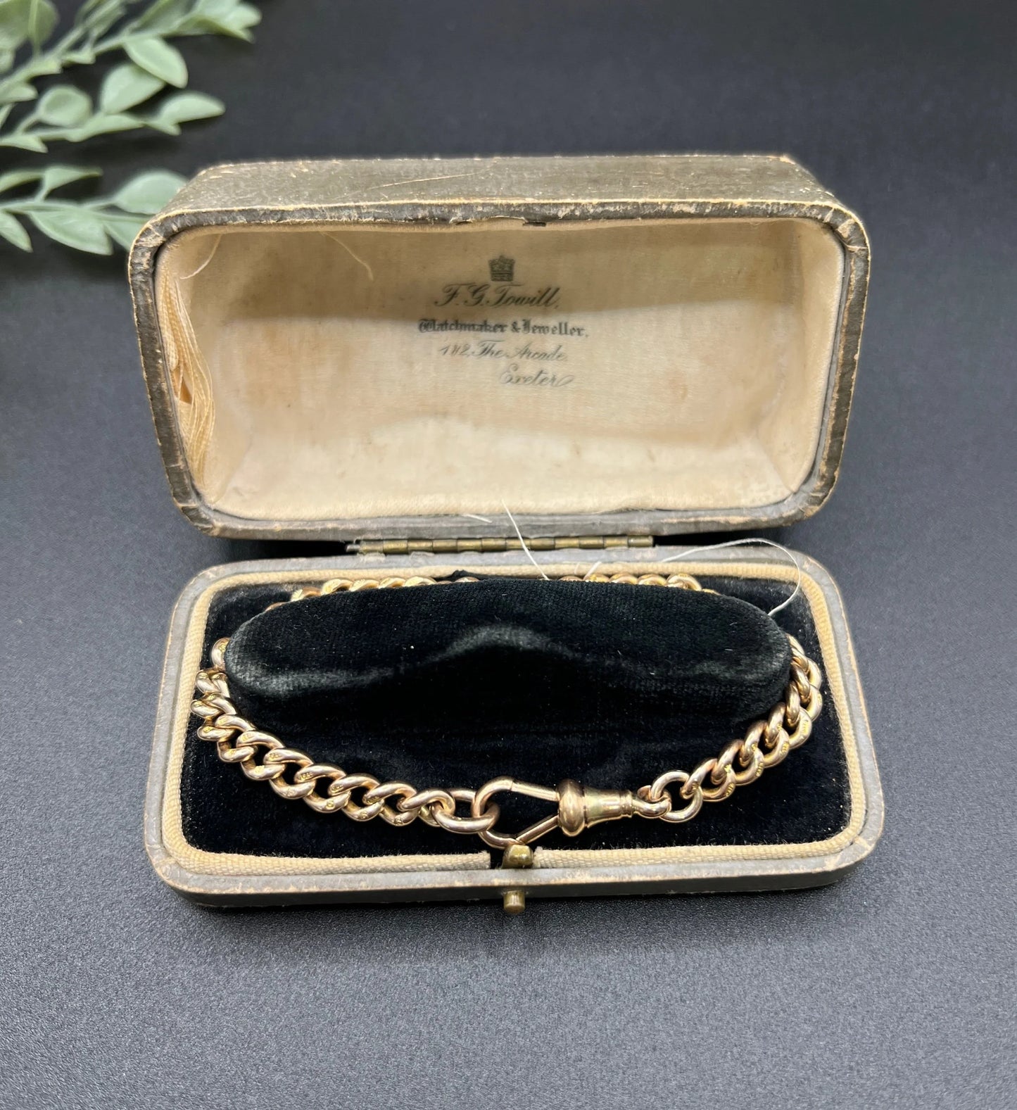 A gold curb link bracelet with a lobster claw clasp, in an antique bracelet box
