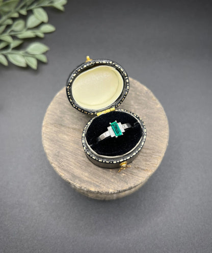 A five stone emerald cut emerald and baguette and square cut diamond ring in platinum, in a ring box