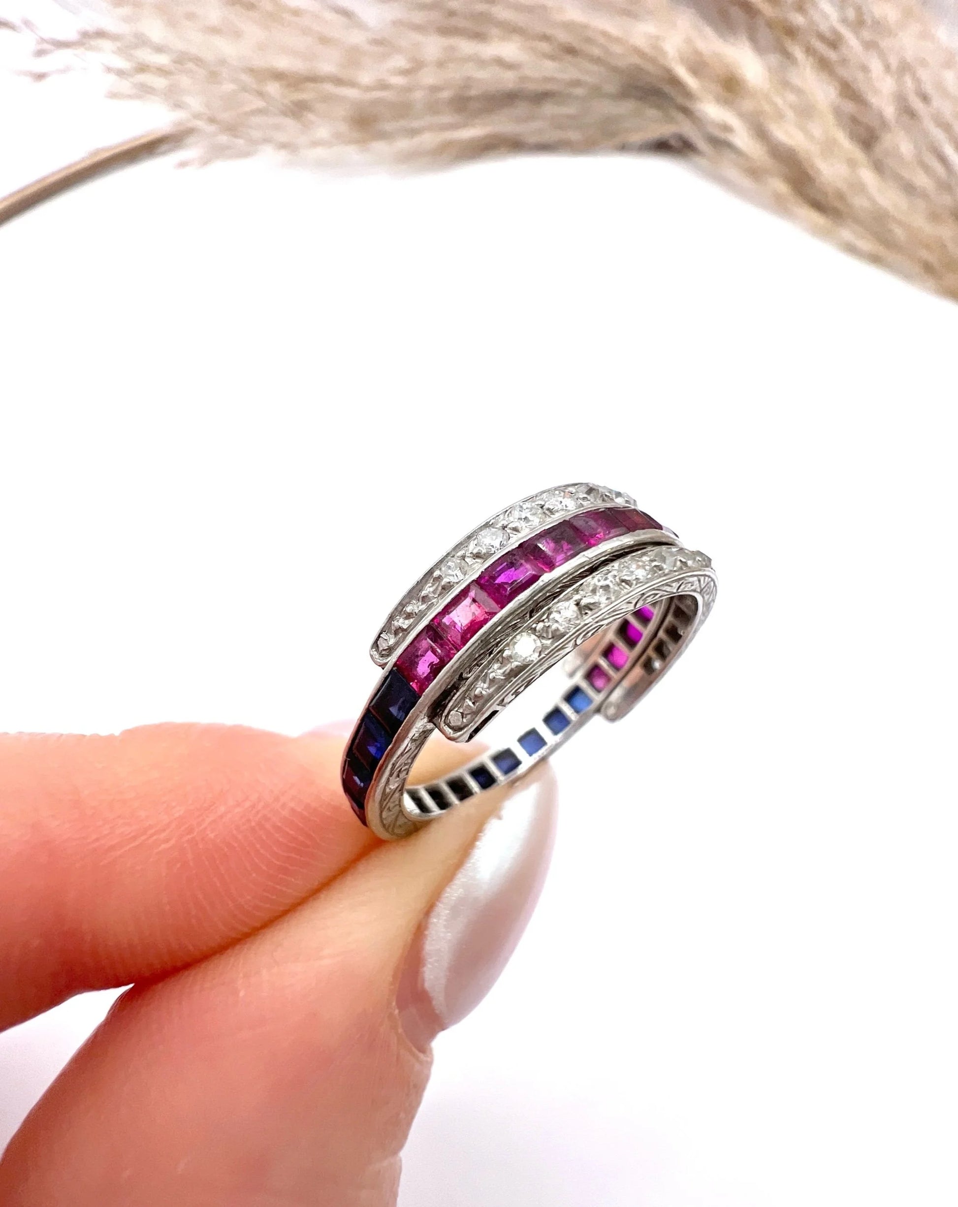 A platinum night and day flip band ring set with diamonds, sapphires and rubies, held in a hand