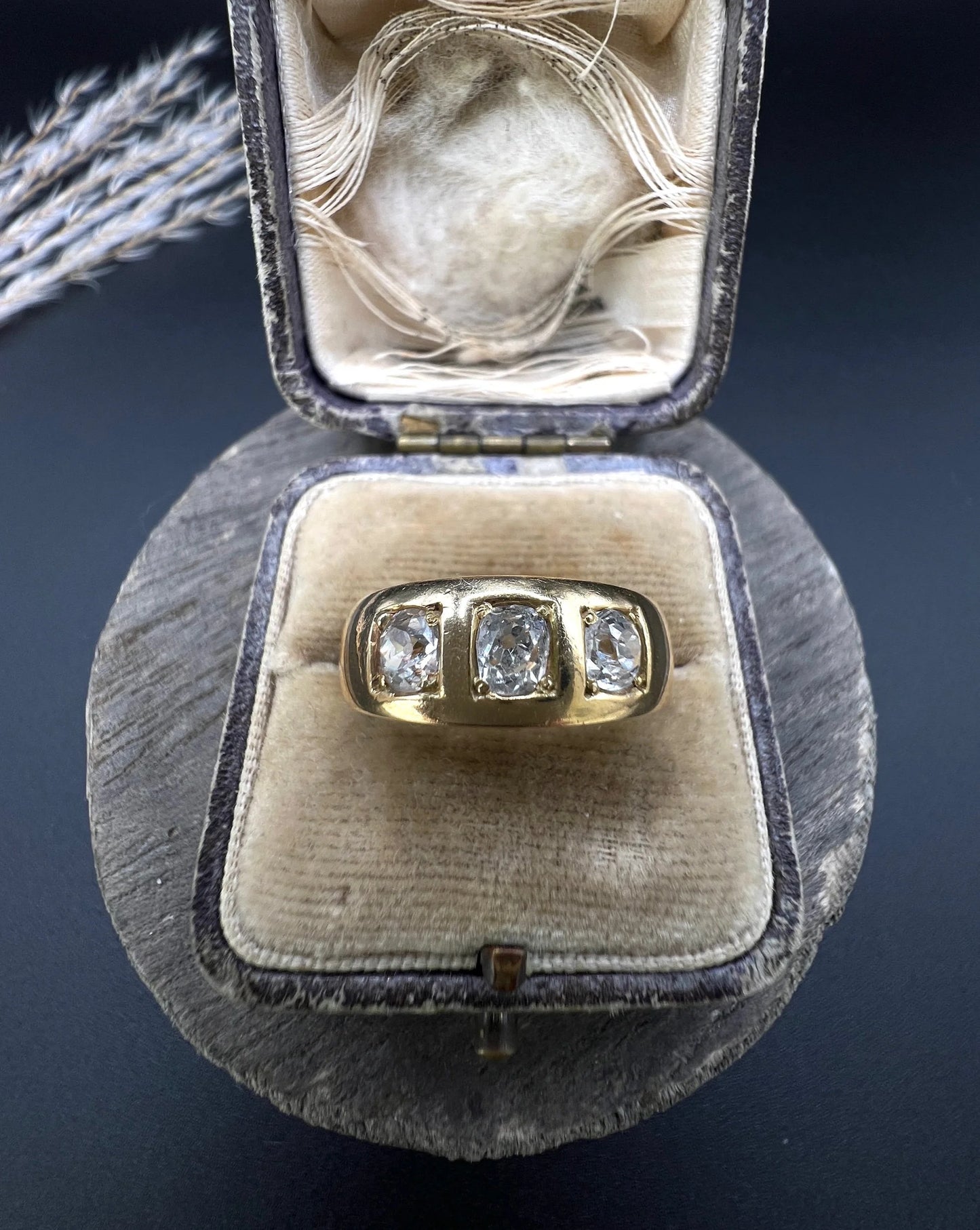 A three stone old cut diamond ring in yellow gold, in an antique ring box