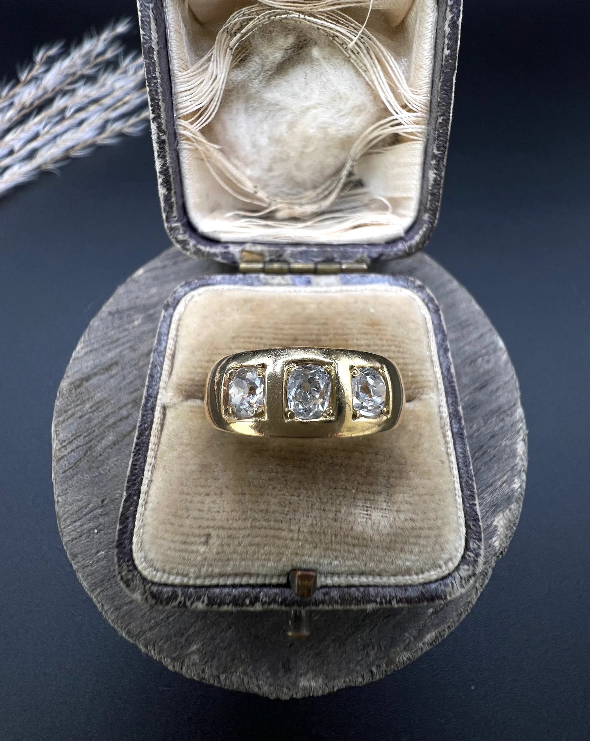 A three stone old cut diamond ring in yellow gold, in an antique ring box