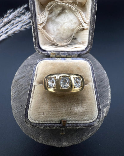 A three stone old cut diamond ring in yellow gold, in an antique ring box