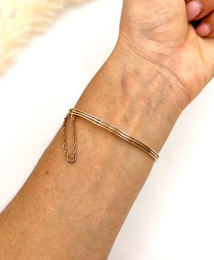 A yellow gold peridot, amethyst and pearl bangle bracelet, modelled on a wrist