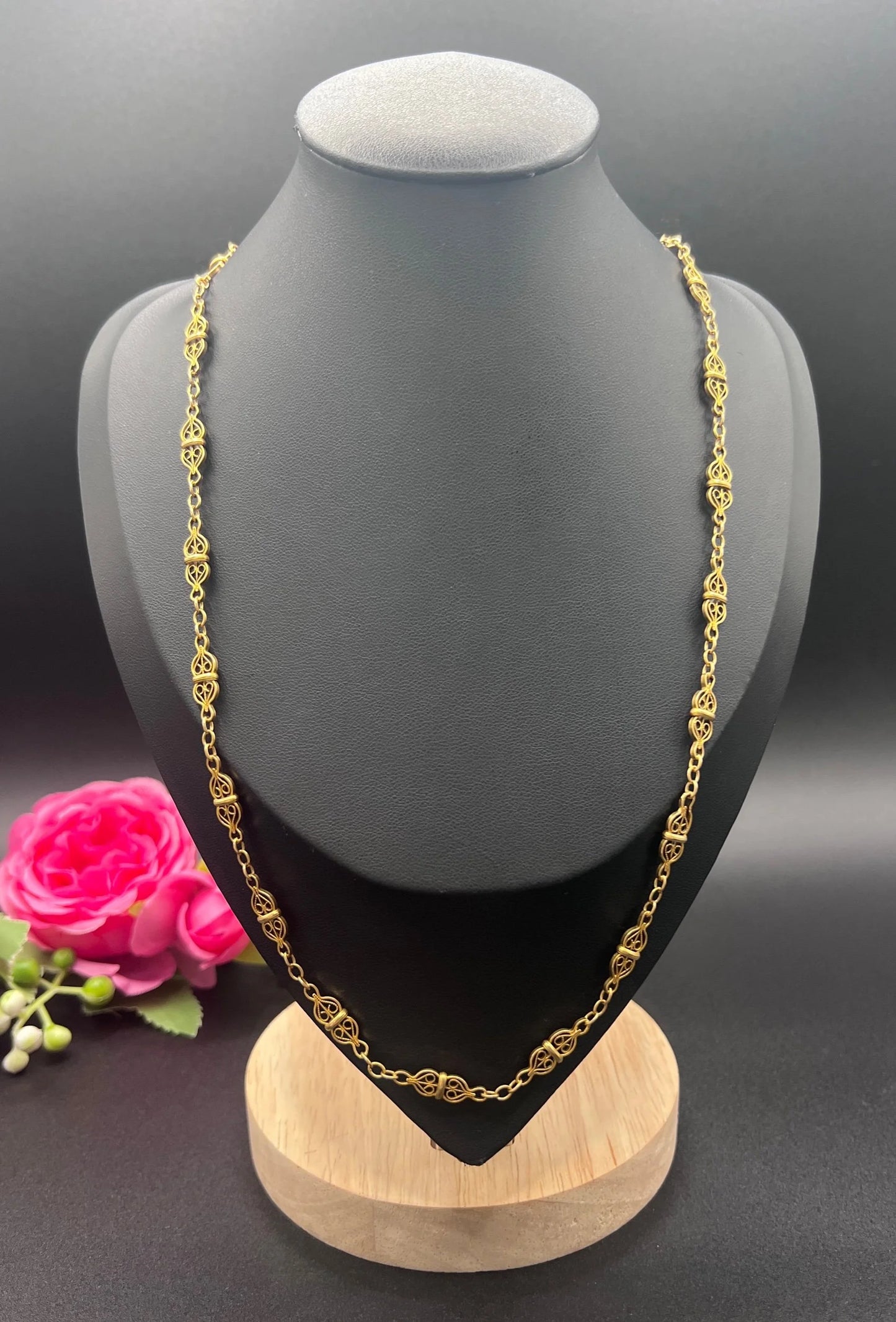 A yellow gold fancy link chain necklace, on a black jewellery bust