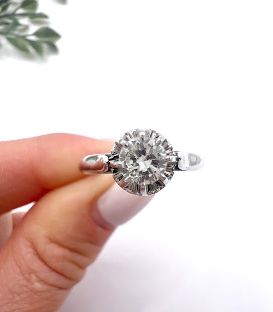 A solitaire round diamond ring in white gold, held in a hand