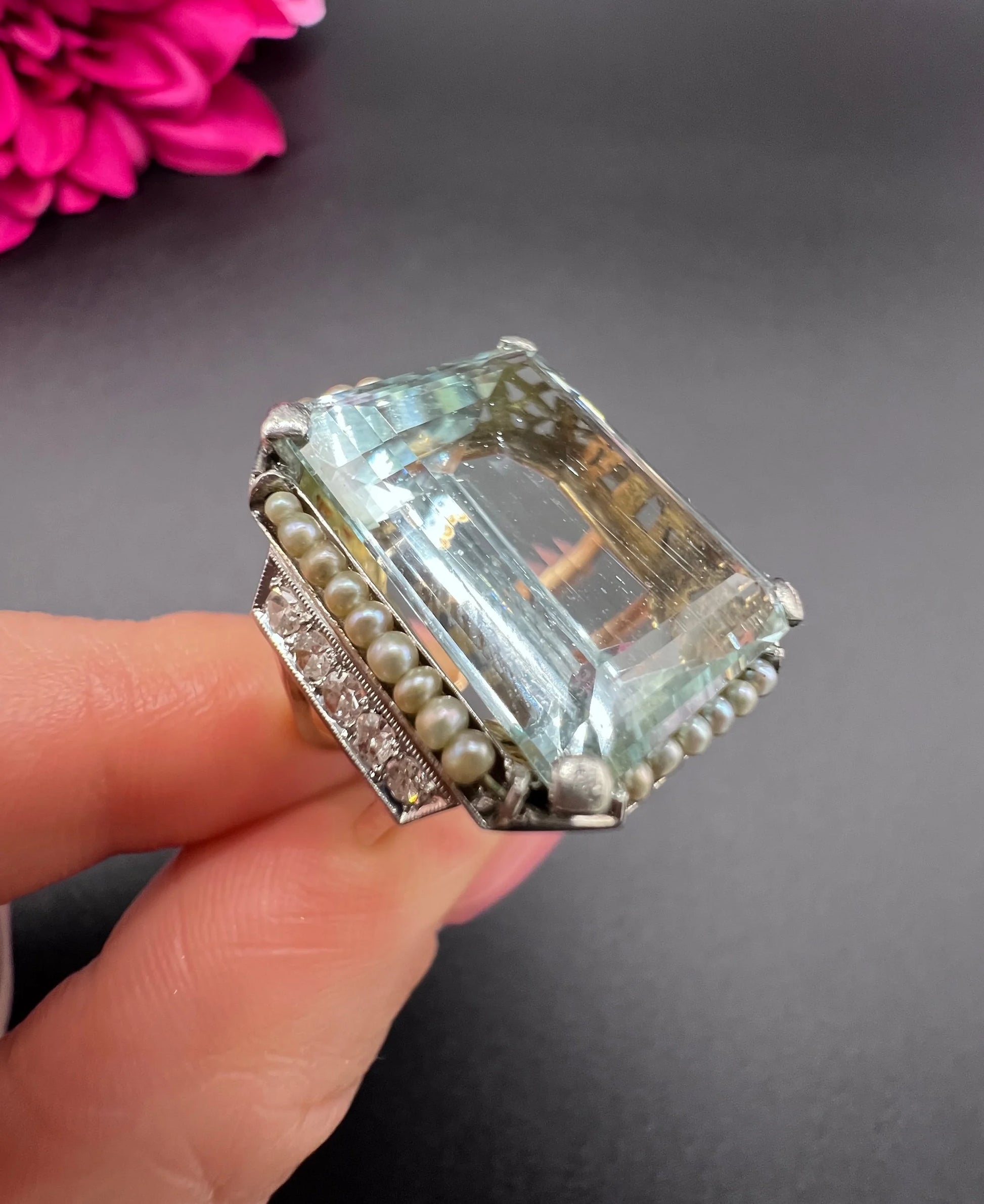 An aquamarine, pearl and diamond large cocktail ring in yellow gold and platinum, held in a hand