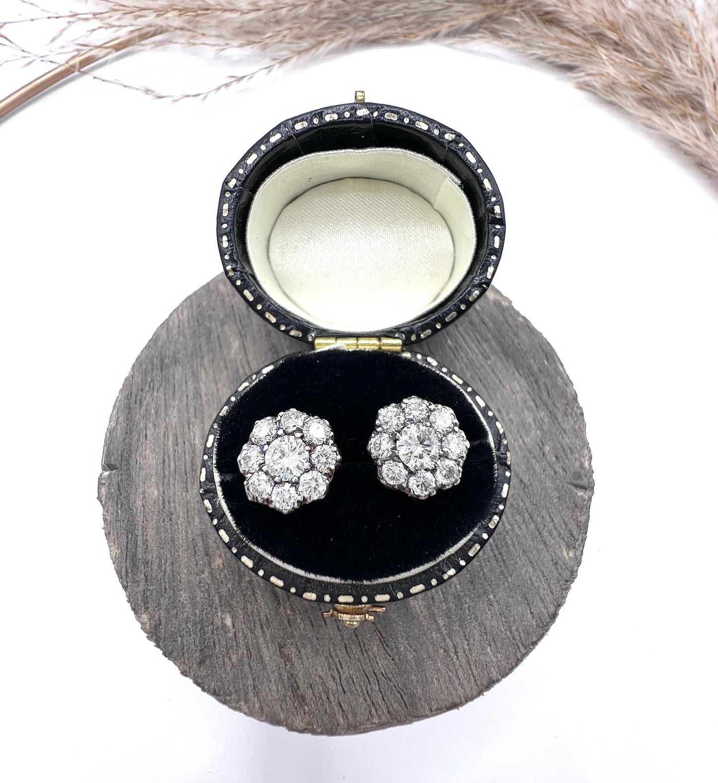 A pair of diamond daisy cluster stud earrings in yellow and white gold, in an earring box