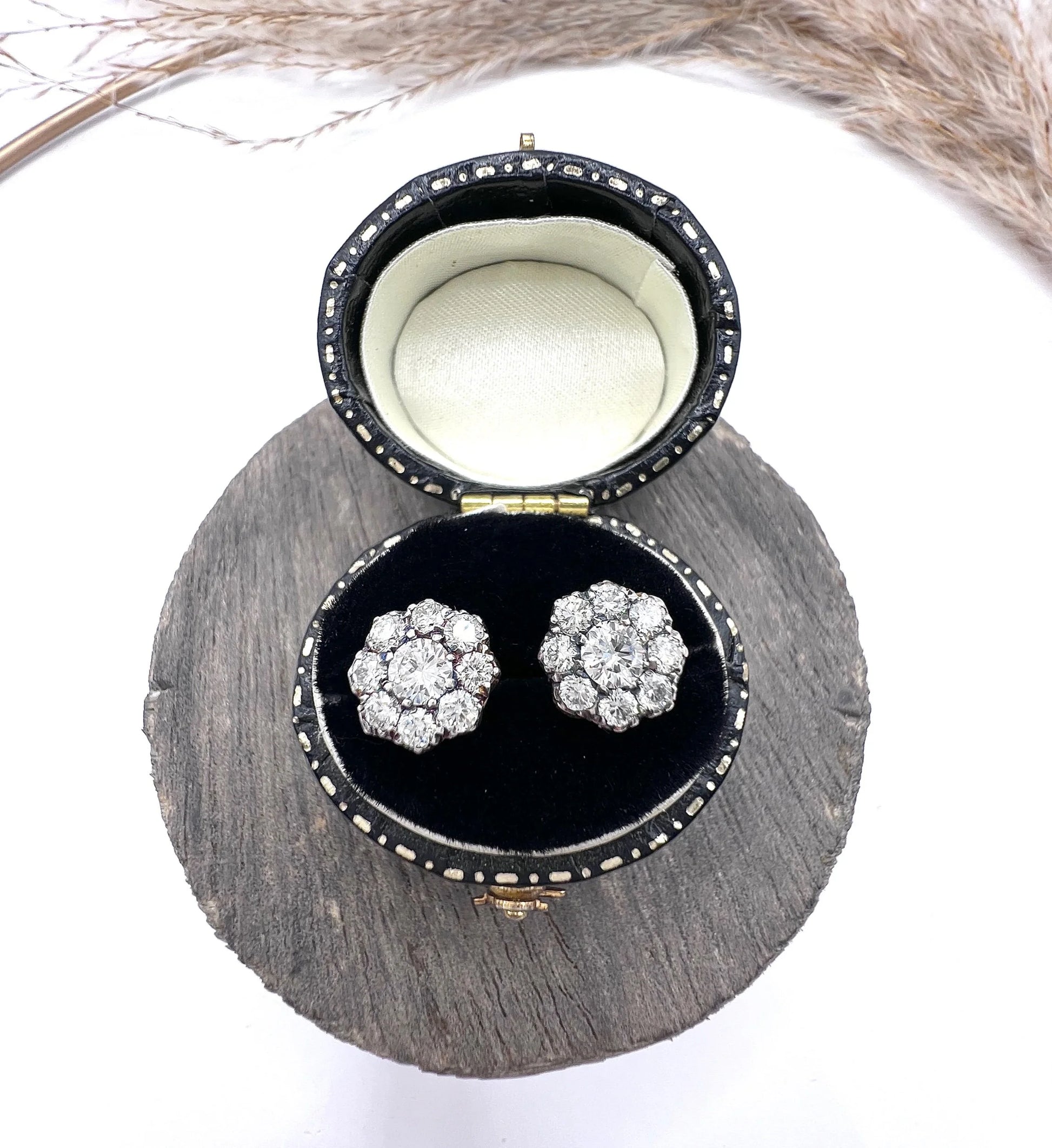 A pair of diamond daisy cluster stud earrings in yellow and white gold, in an earring box