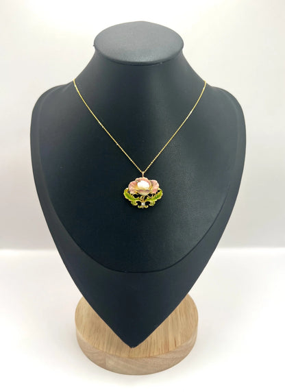 An enamel, diamond and pearl flower pendant with a gold chain, on a black jewellery bust