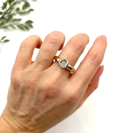 A single stone brilliant cut diamond ring bezel set in yellow gold, modelled on a hand