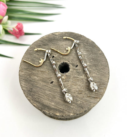 A pair of diamond drop earrings in yellow gold and platinum, on a wooden item